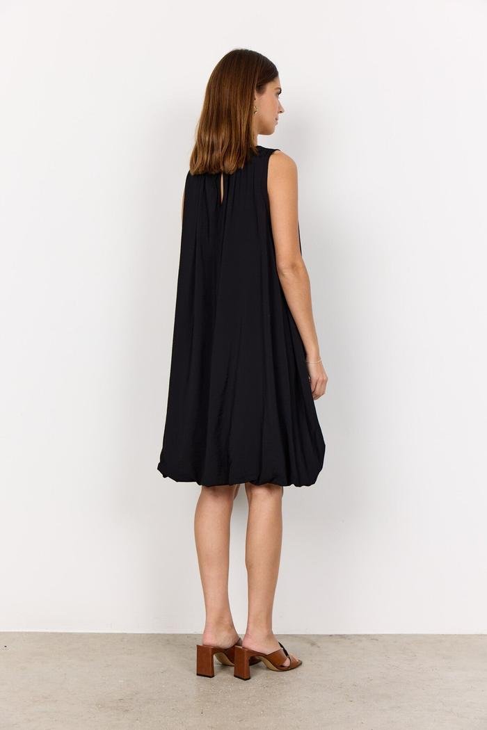 Model from behind wearing a loose-fitting black SC-SIDRA 2 viscose dress with a gathered hem.