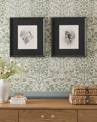 The Winnie framed horse portraits in black frames hang on a green floral wallpapered wall above a wooden dresser. A vase with flowers and stacked woven baskets sit atop, complementing the elegant Winnie wall art display by McGee & Co.