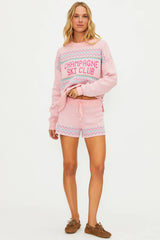 Woman wearing a pink 'Champagne Ski Club' outfit on a white background