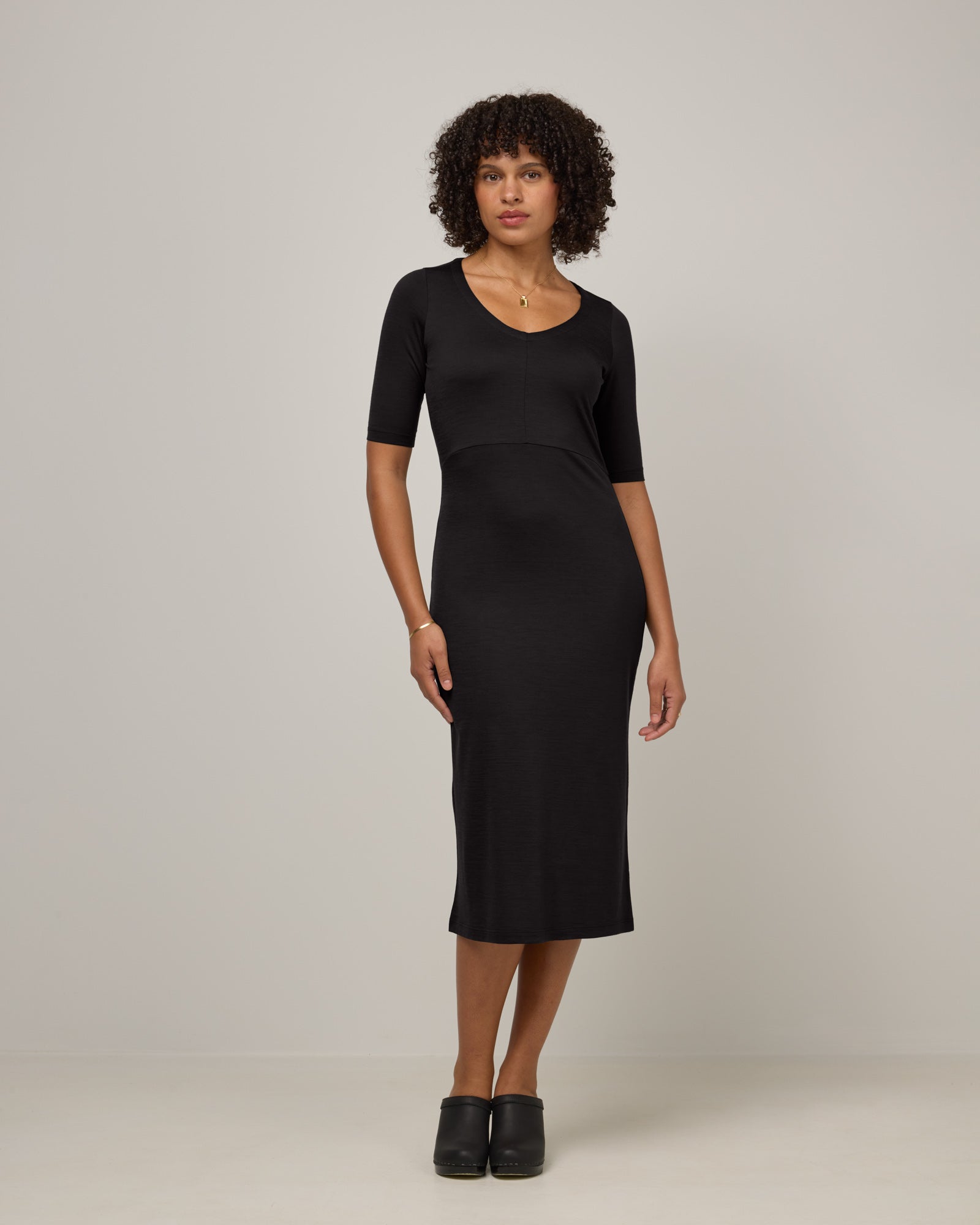 Model wearing London Fitted Dress in Black. London Fitted Dress is a merino wool short sleeve, v-neck, midi fitted dress available in sizes XS-3X Regular, XS-XL Petite.