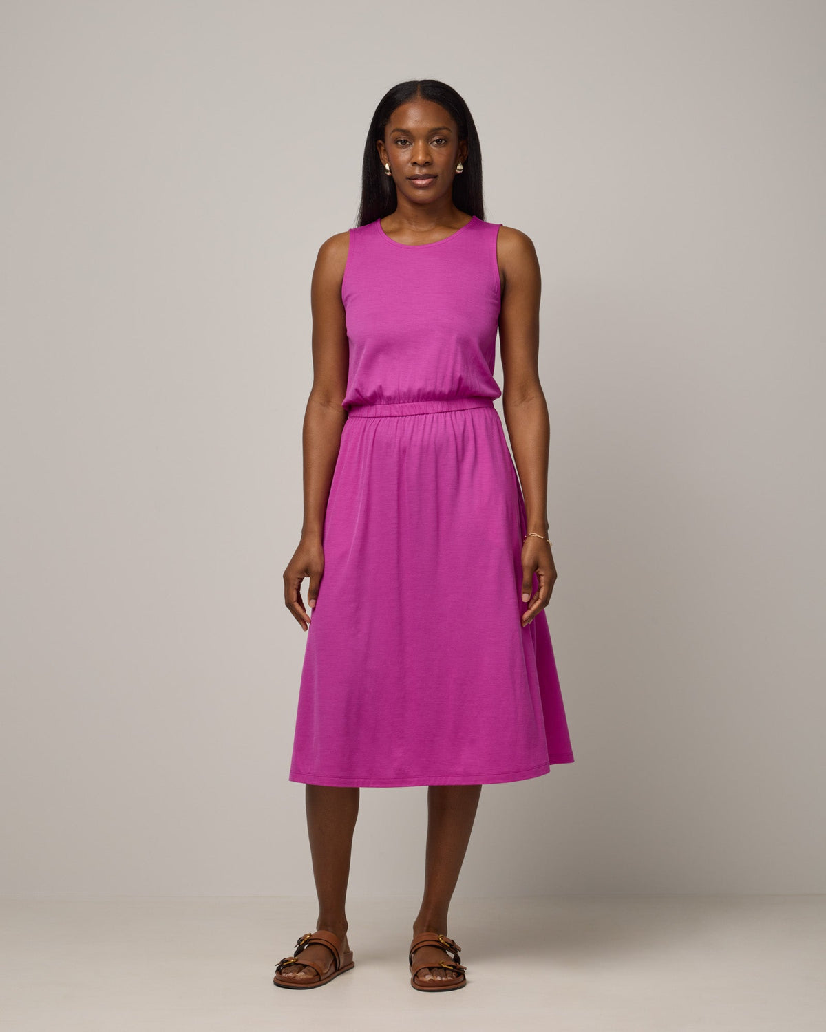 Model wearing Sofia Fit & Flare Dress in Petunia, a bright fuchsia pink-purple color. Sofia Fit & Flare Dress is a merino wool sleeveless, crew neck, midi fit & flare dress with pockets available in sizes XS-XXL.