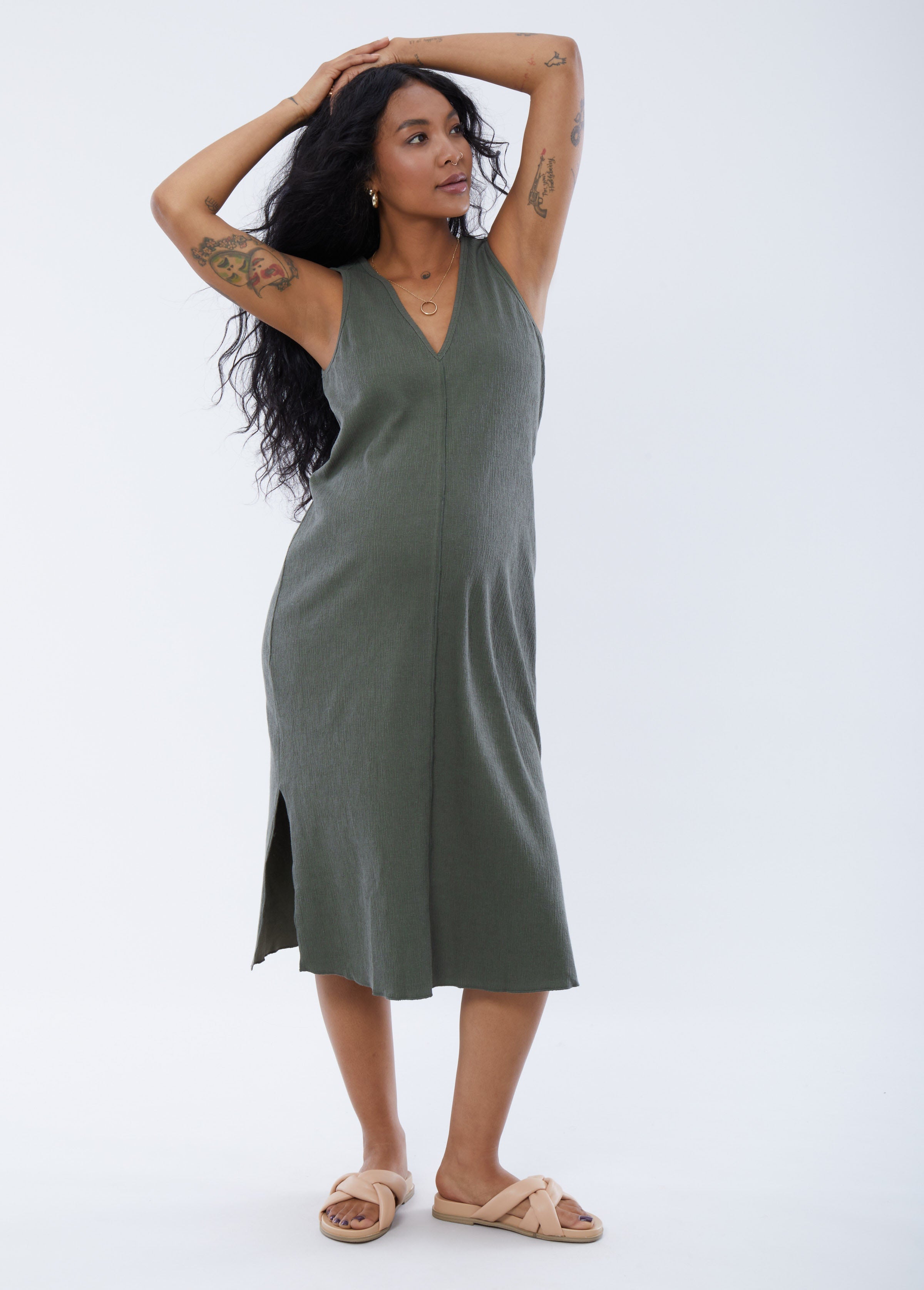 ||Pregnant woman wearing green v-neck sleeveless dress on a plain background