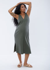 ||Pregnant woman wearing green v-neck sleeveless dress on a plain background