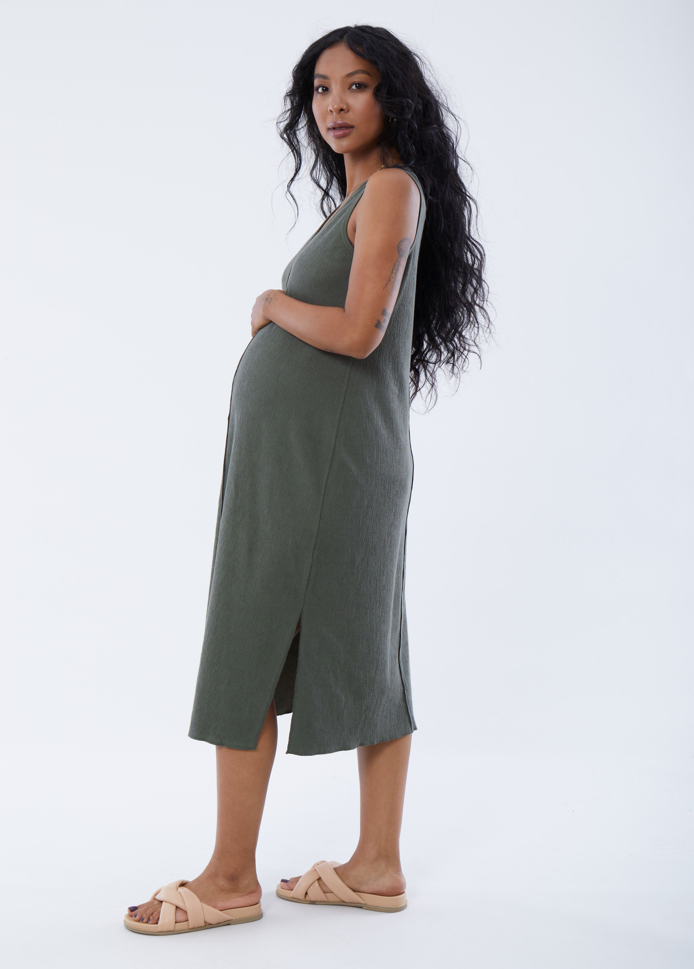 ||Pregnant woman wearing green v-neck, sleeveless dress on a plain background
