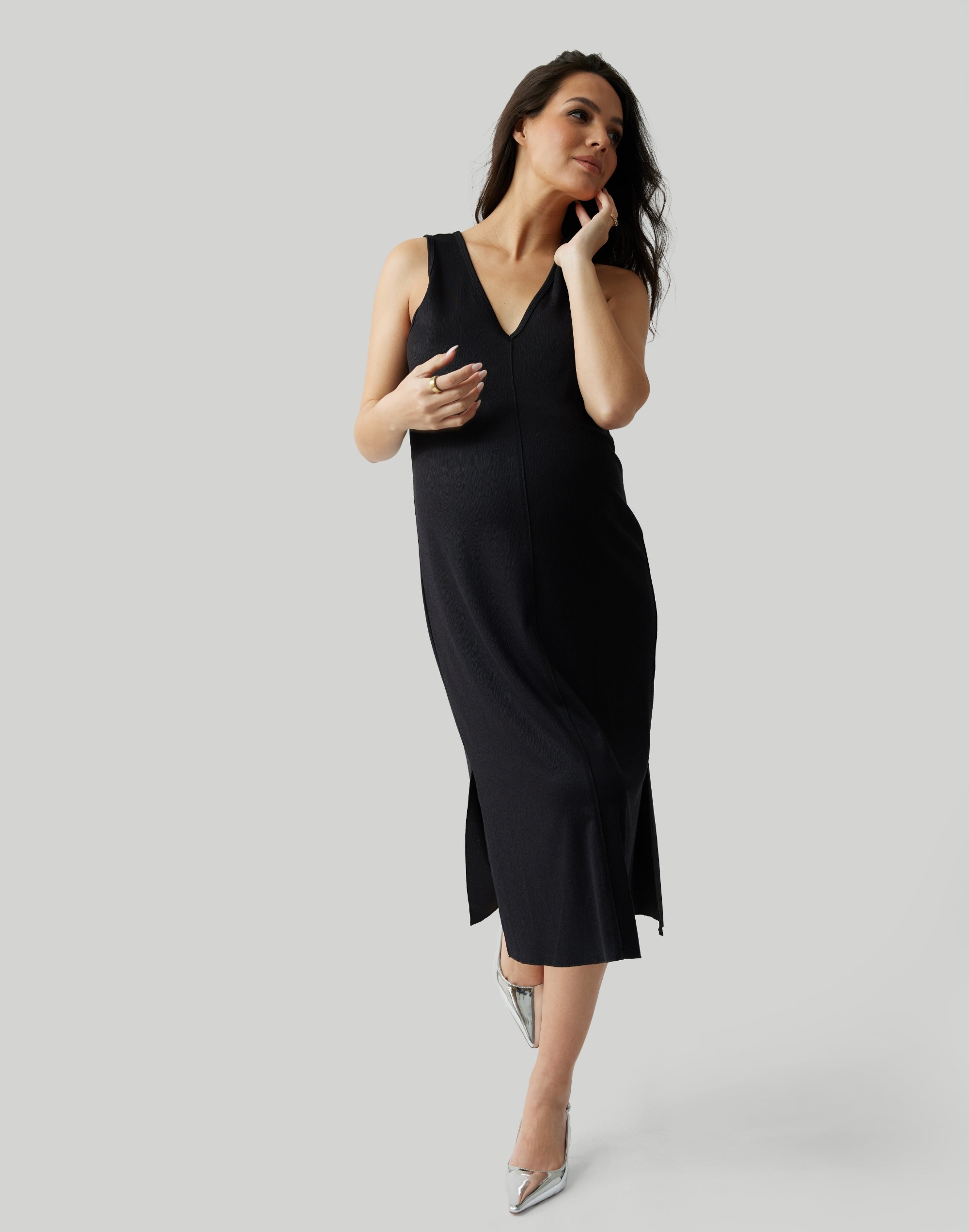 ||Pregnant woman wearing black v-neck, sleeveless dress on a plain background