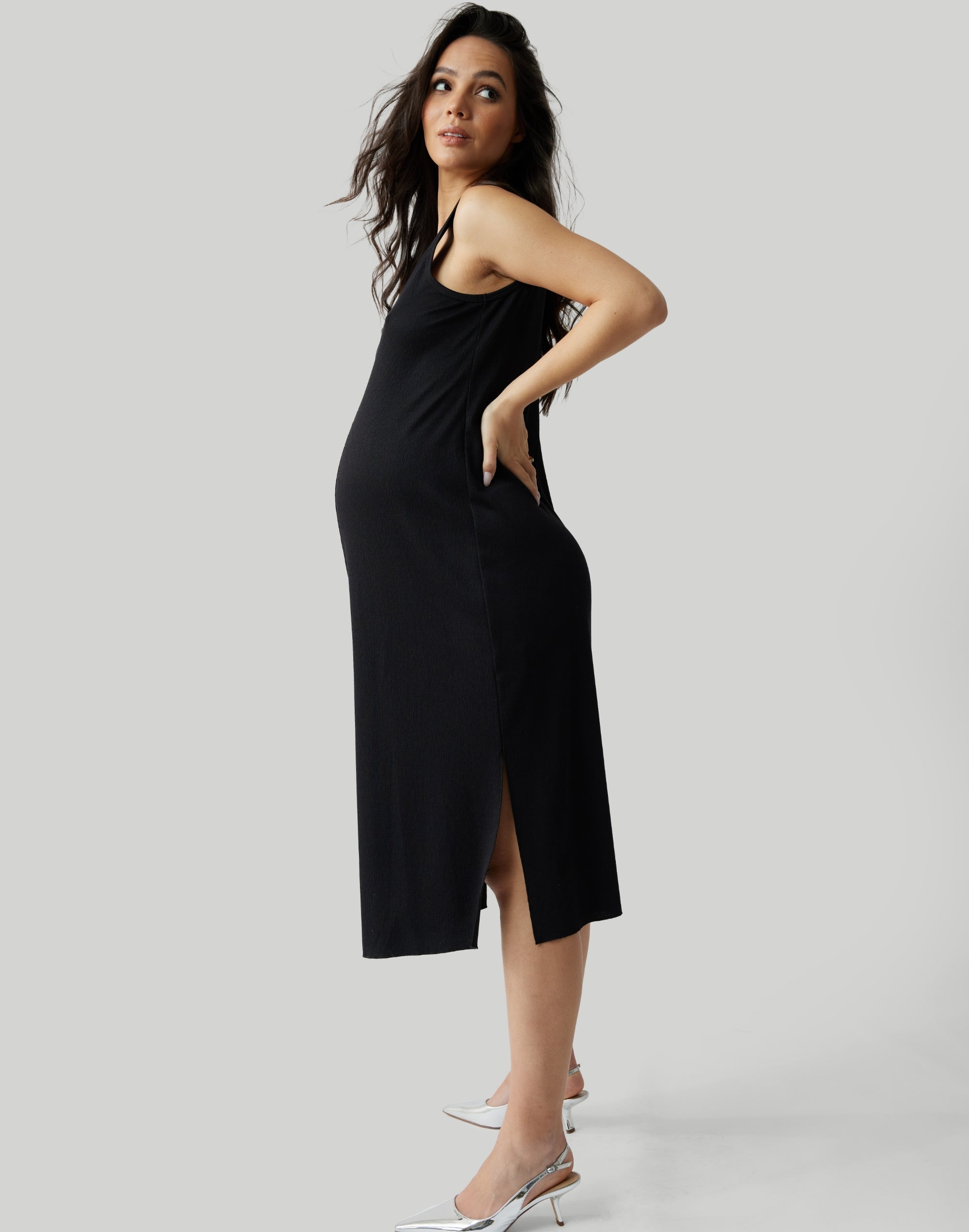 ||Pregnant woman wearing black v-neck, sleeveless dress on a plain background