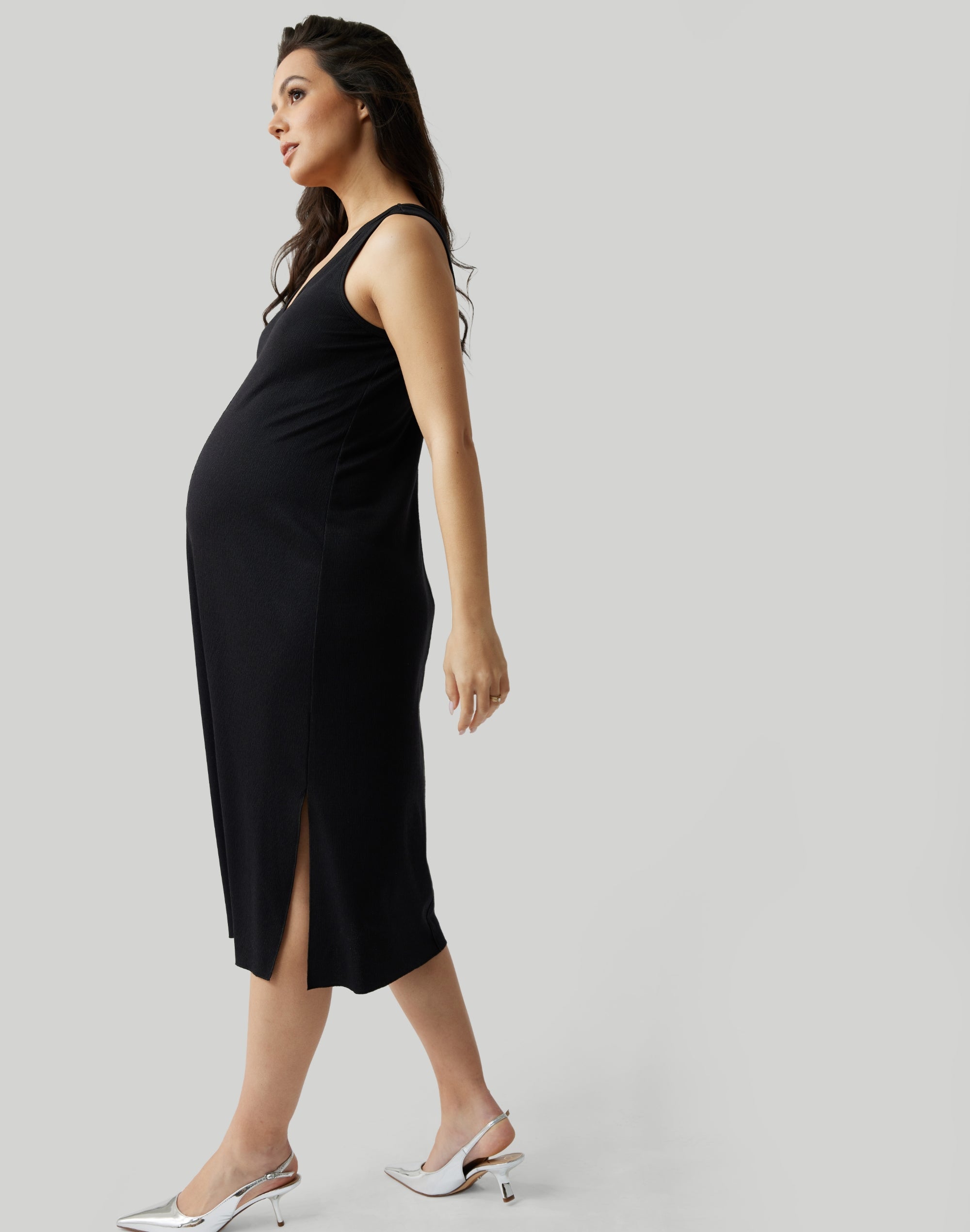 ||Pregnant woman wearing black v-neck, sleeveless dress on a plain background