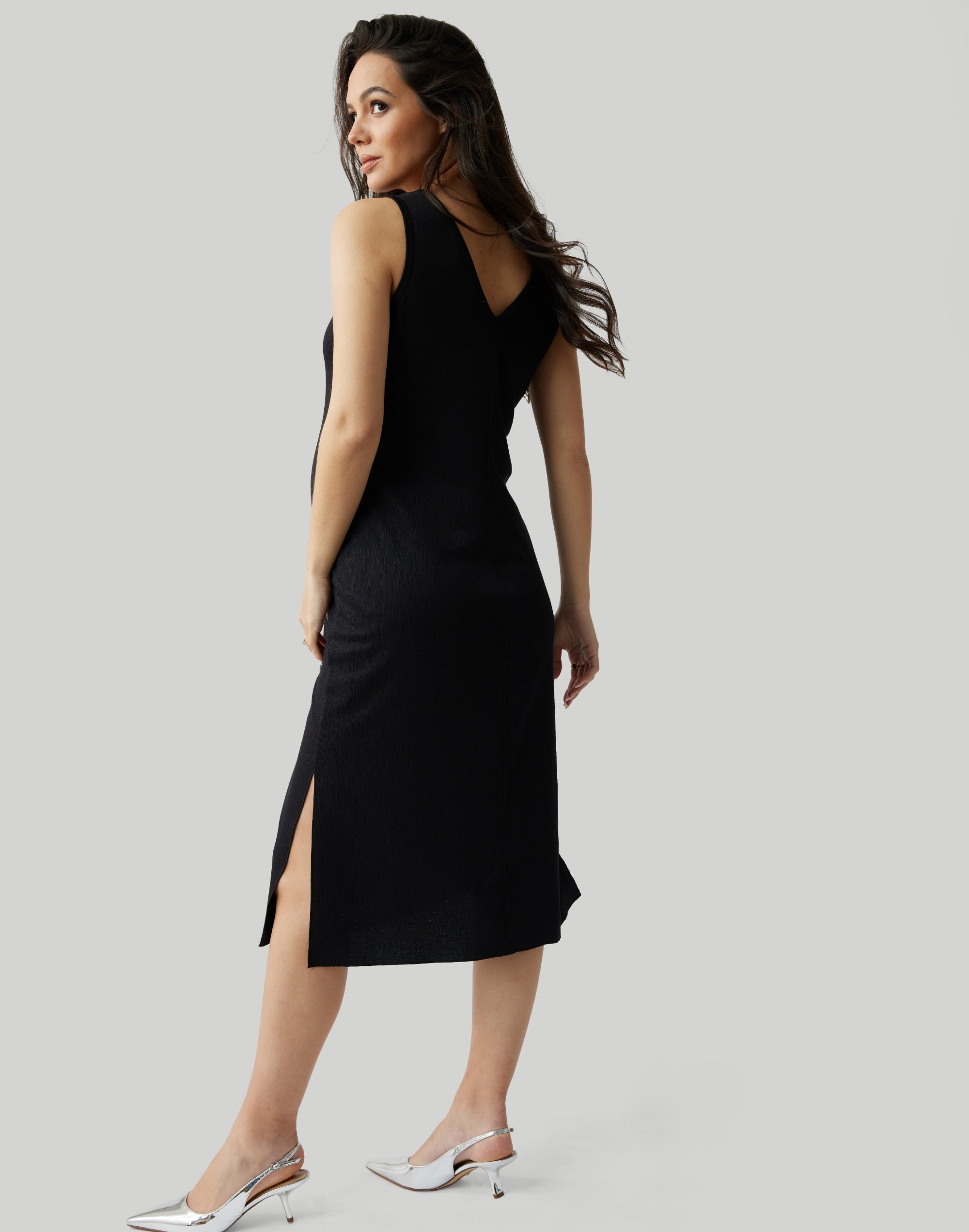 ||Pregnant woman wearing black v-neck, sleeveless dress on a plain background