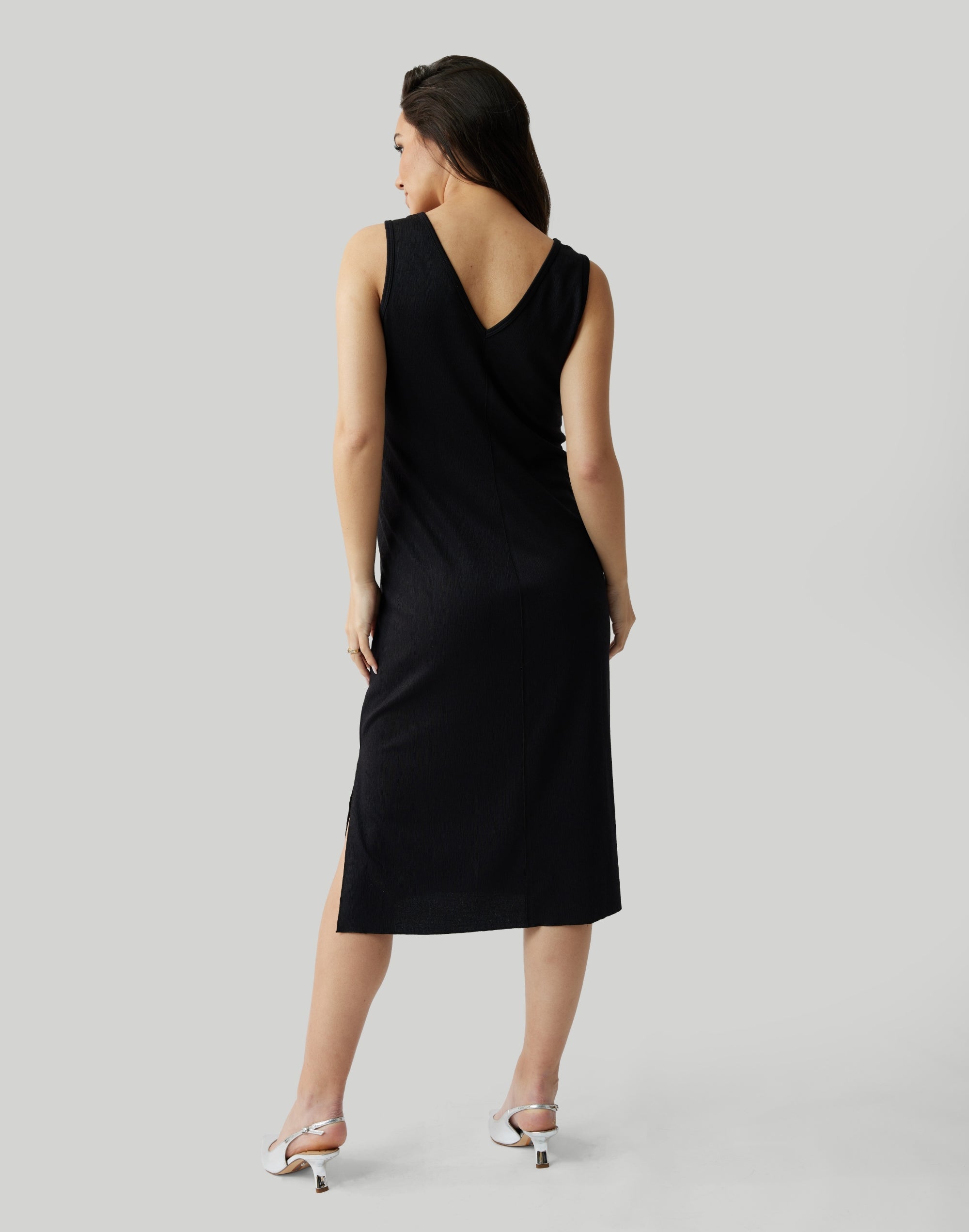||Pregnant woman wearing black v-neck, sleeveless dress on a plain background