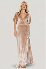Front view of champagne velvet wrap maxi dress on model showing V-neckline, adjustable waist tie, tulip hem, mid-length bell sleeves, and soft pile sheen.