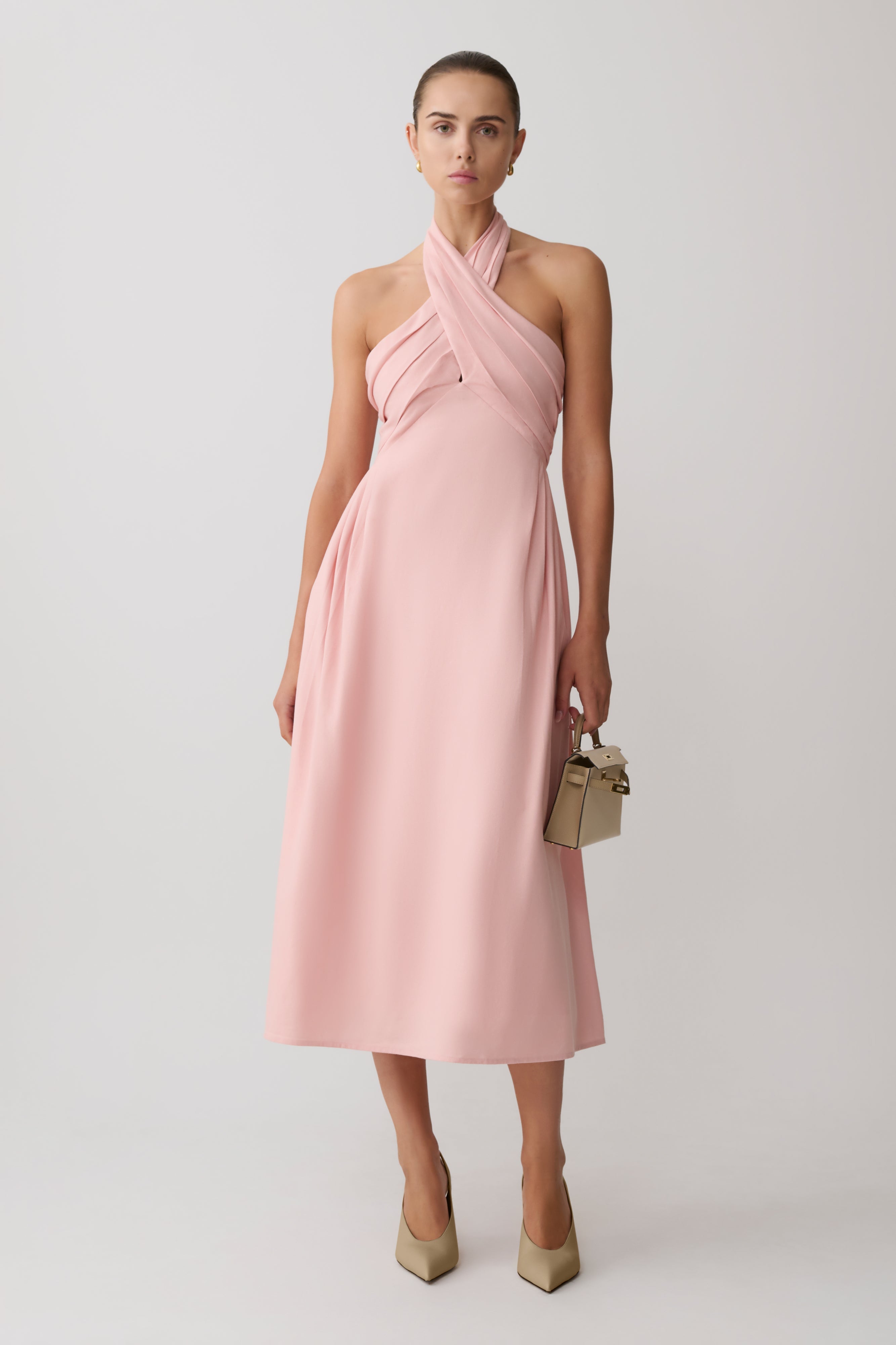 Woman wearing a pink croos over hallter maxi dress.