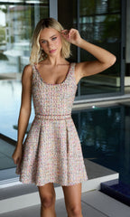 A woman wearing the Ava Presley 26722 Tweed-Jacket Short Party Dress poses by an indoor pool, one hand to her ear and looking at the camera.
