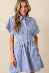 A cropped view of the blue stripe mini dress, emphasizing the pleated detailing and the flow of the fit-and-flare skirt. The vertical stripe pattern elongates the design.