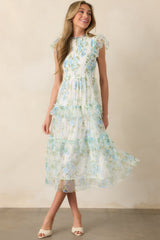 A full-body front view of a blue dress featuring a fully smocked bodice, delicate tulle flutter sleeves, a round ruffle neckline, and a tiered skirt design.