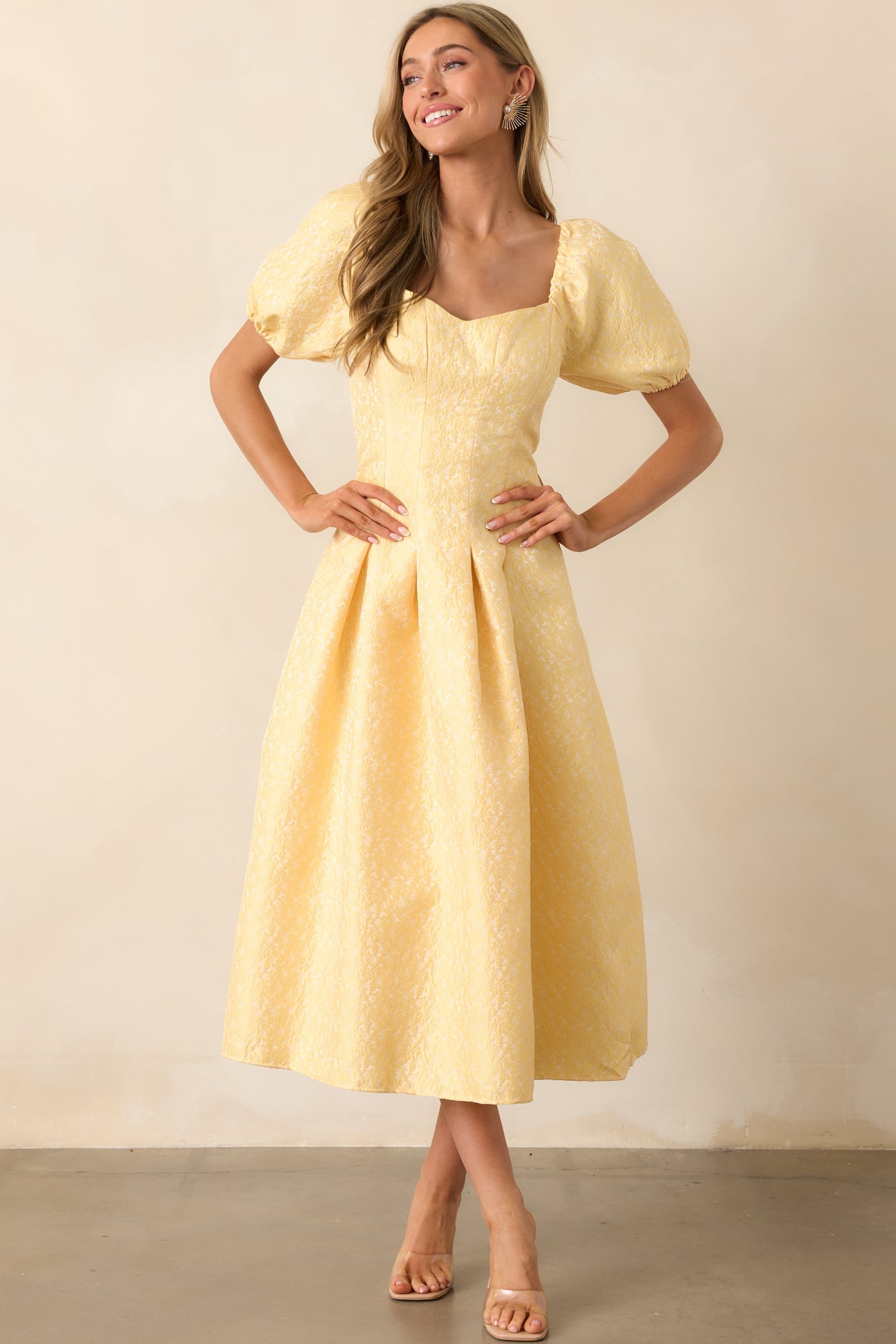 A timeless maxi dress in yellow floral jacquard, featuring delicate details like puff sleeves and a fitted bodice.