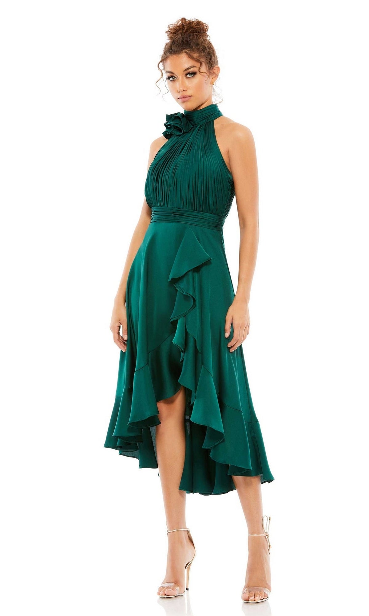 A woman wears the Mac Duggal 49488 high-low wedding guest dress in emerald green with a sleeveless, ruffled design and high neckline, paired elegantly with strappy nude heels.