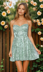 Woman wearing a light green floral dress standing in front of flowers