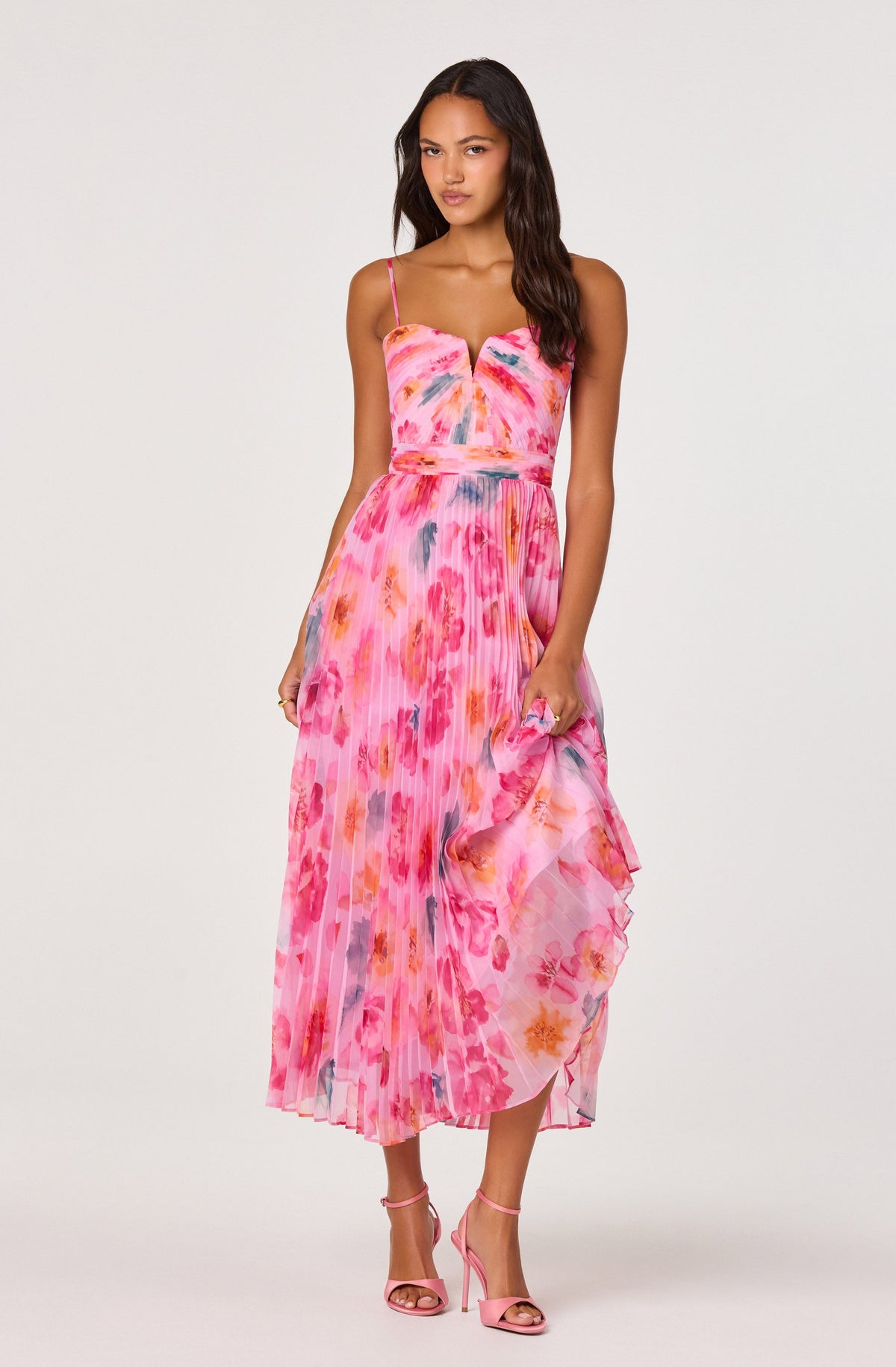 Woman in pink tie-dye spaghetti strap maxi dress with ruffled hem, pink high-heeled sandals.