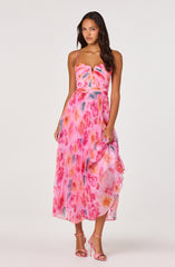 Woman in pink tie-dye spaghetti strap maxi dress with ruffled hem, pink high-heeled sandals.