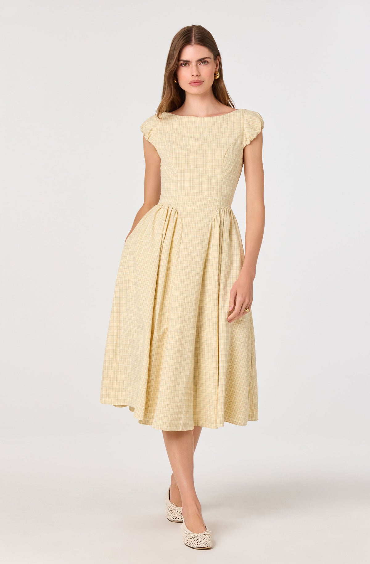 Woman in a yellow plaid midi dress with puffed sleeves and a full skirt.