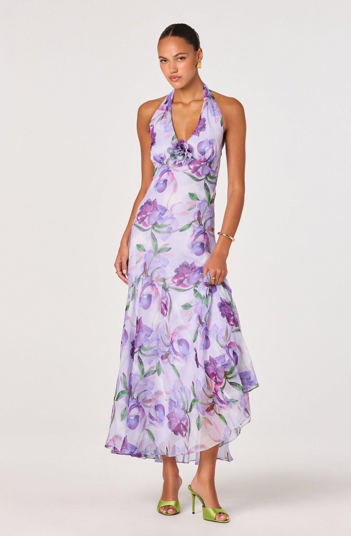 Woman in a long, sleeveless purple and green floral dress with halter neckline.