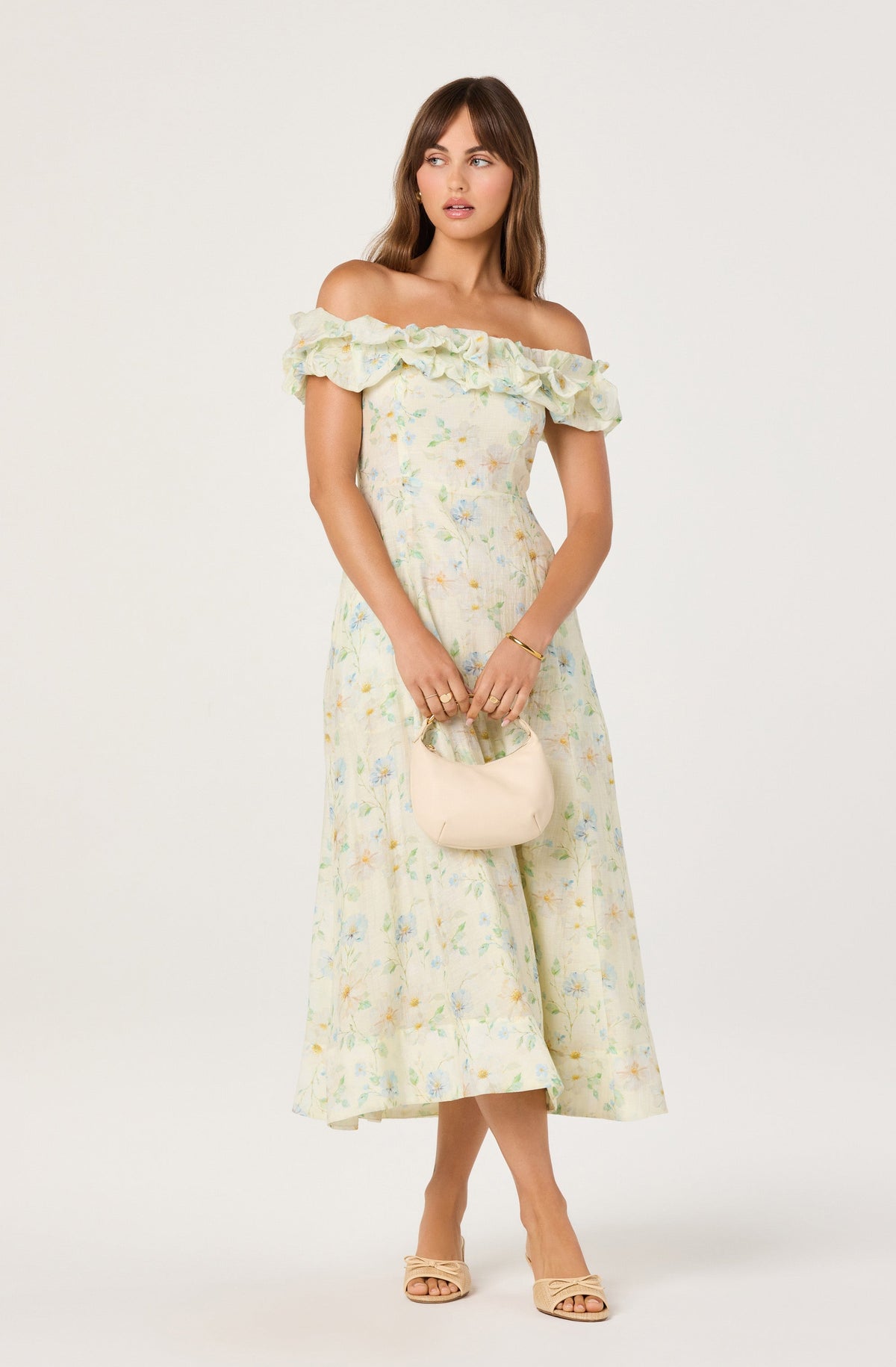 Light-colored floral off-shoulder dress with ruffle detail, beige heels, and a small beige purse.