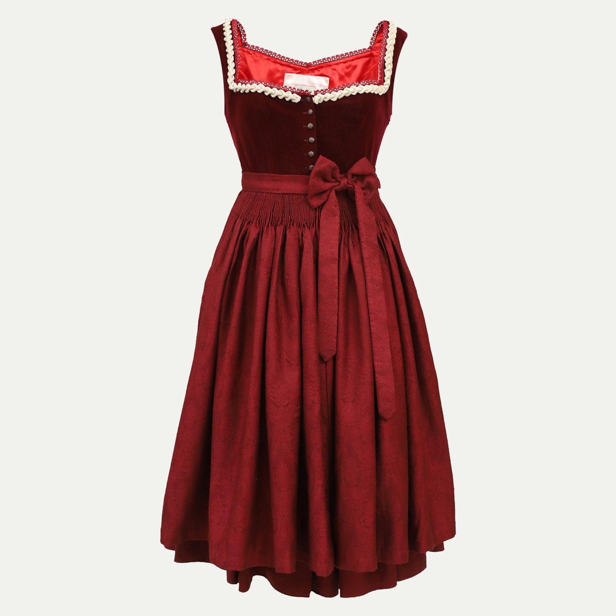 Classic red sleeveless dirndl dress featuring a fitted bodice with button detail, contrasting trim at the neckline, and a wide skirt cinched with a sash bow