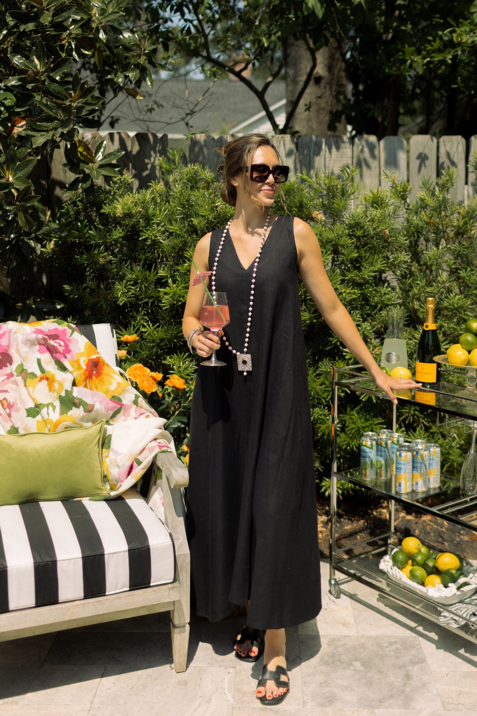 Woman posing outdoor wearing black linen Katherine dress paired with Boho necklace. --Arte Italica and Crown Linen Designs