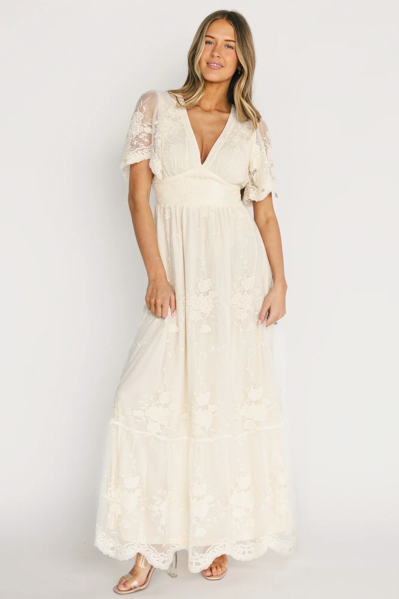 Front view of Rosalia Lace Maxi Dress in vintage cream on model, showing V-neck, crochet circle trim, fitted underbust panel, and scalloped sleeves.