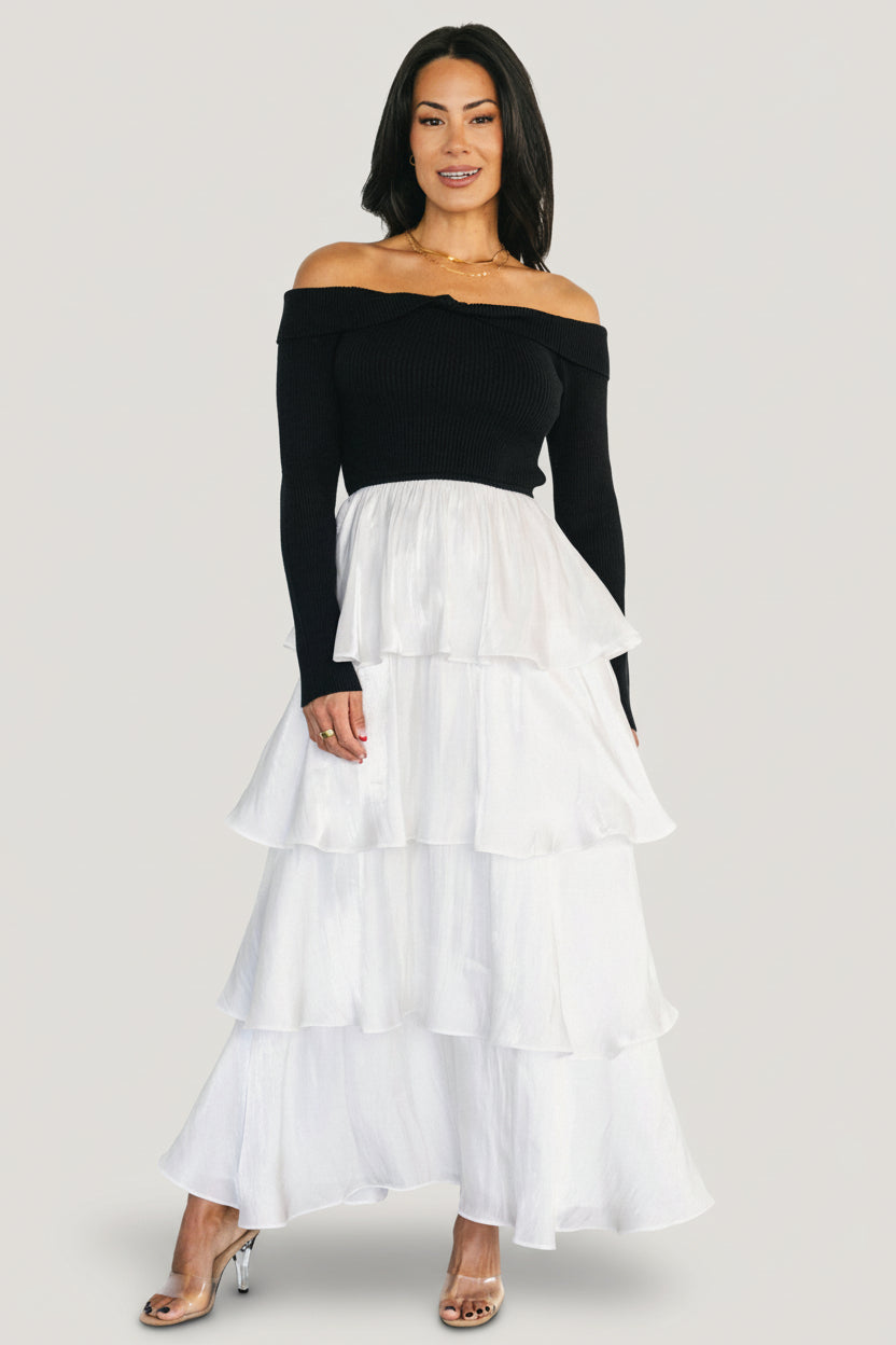 Front view of Maelie Tiered Maxi Dress on model; black ribbed off-shoulder sweater bodice with white tiered satin maxi skirt, full length.