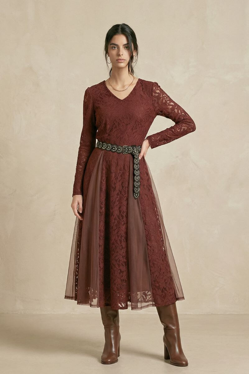A model poses in a burgundy lace V-neck midi dress styled with a wide embellished belt and knee-high boots, highlighting the dress’s romantic lace texture and soft drape.