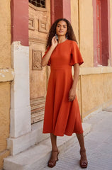 Woman wearing the Selina Dress sewing pattern from The Patterns Room on The Fold Line. A dress pattern made in tencel (lyocell), crepe, viscose, or poplin fabric, featuring a round neckline, fitted bodice, petal sleeves, A-line skirt, and midi length.
