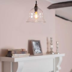 Pendant light with clear glass shade hanging above a fireplace.