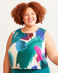 Woman wearing a colorful sleeveless top with abstract patterns on a plain background.  This top is the Thorndike Tank sewing pattern from Cashmerette.
