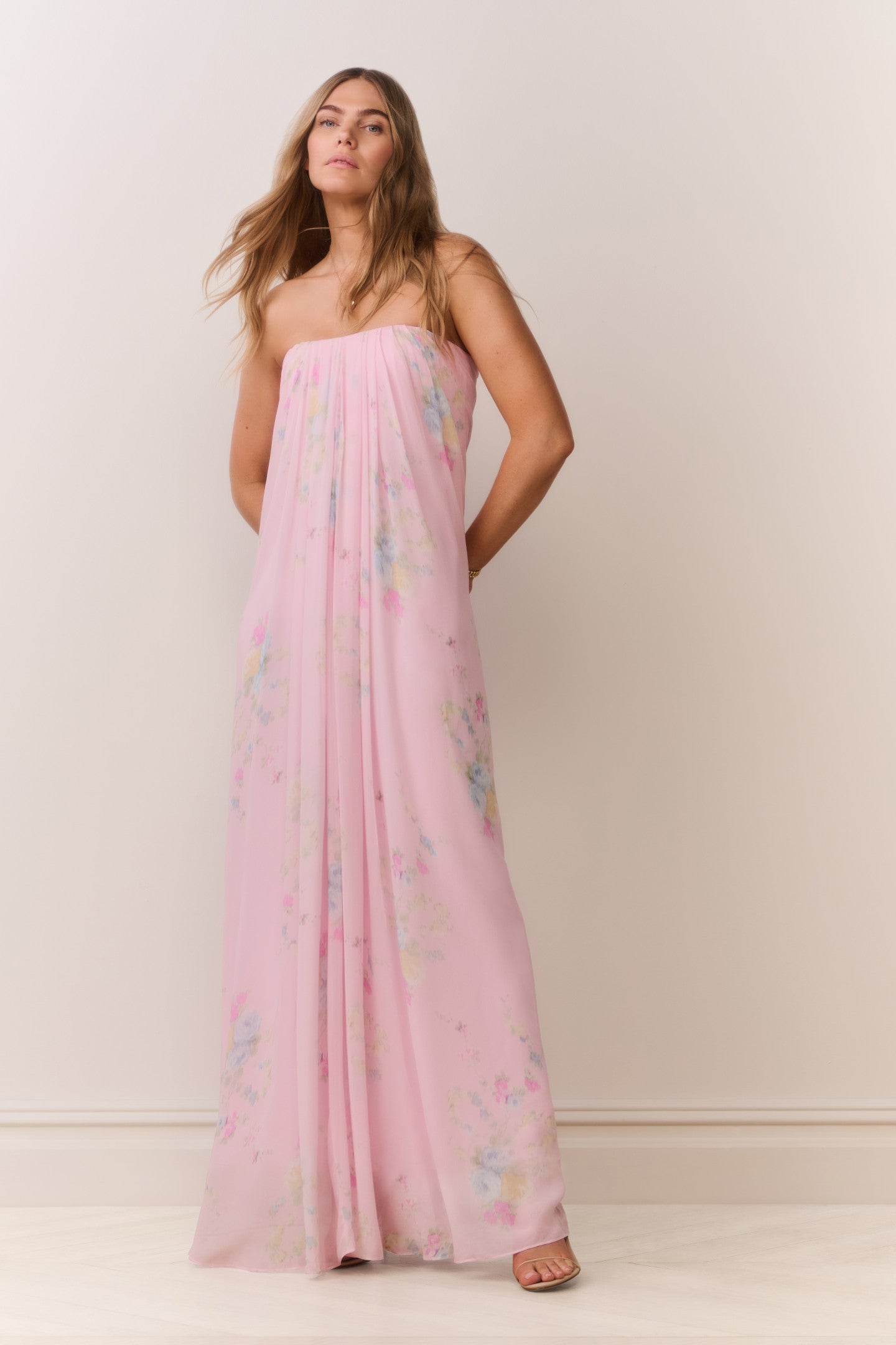 Woman wearing a pink strapless dress with floral patterns on a plain background