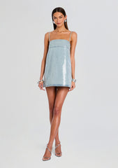 Model wearing Nadiya Denim Dress a pale blue mini denim dress with thin straps and sequin embellishments.