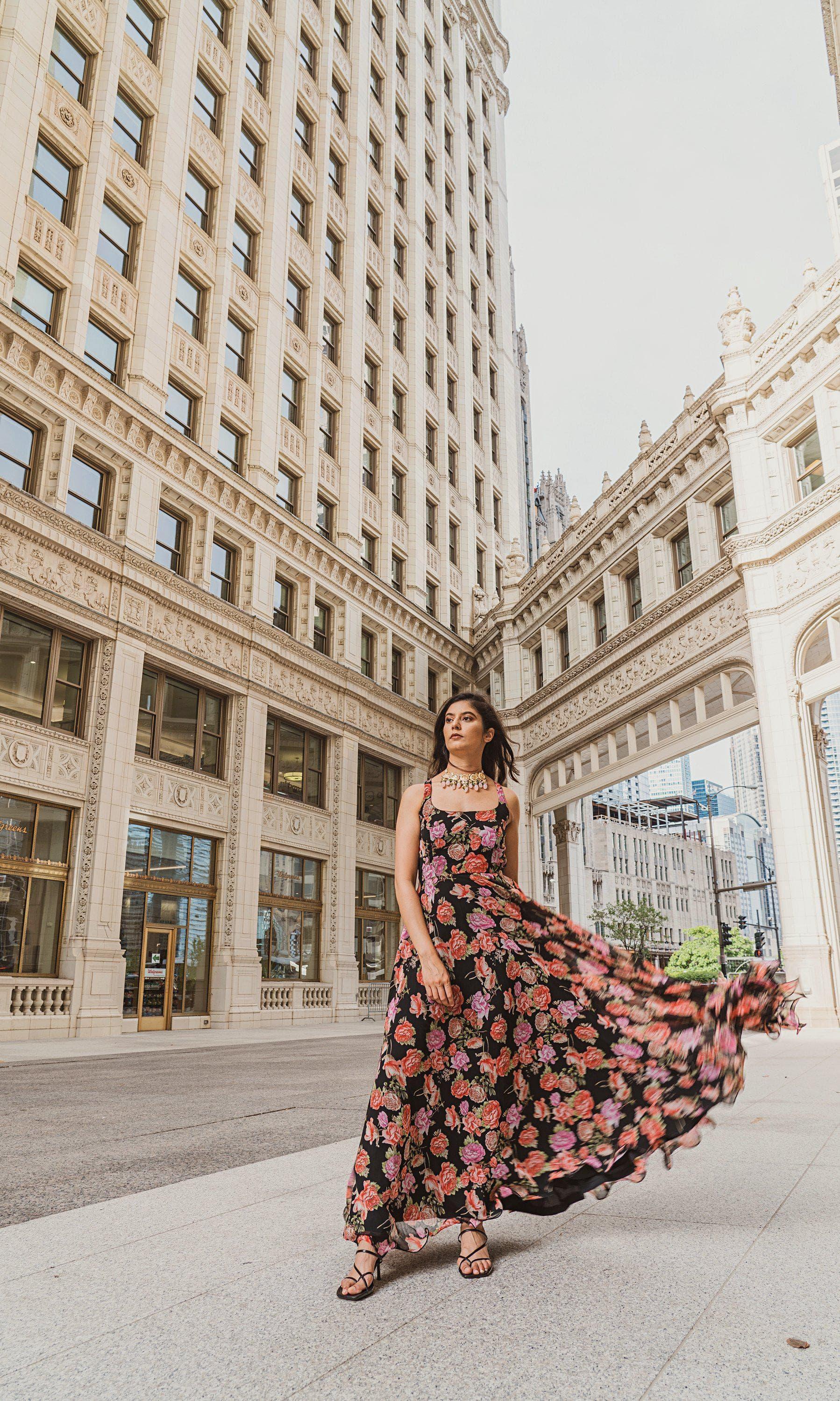 Woman in a flowing black georgette long dress with vibrant magenta and purple ikat-inspired floral print.