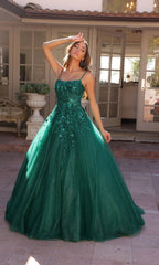 A woman poses outside before glass doors wearing the Embellished Hunter Green Long Prom Ball Gown H1464—a floor-length, sequin dress with thin straps and sparkling embellishments.