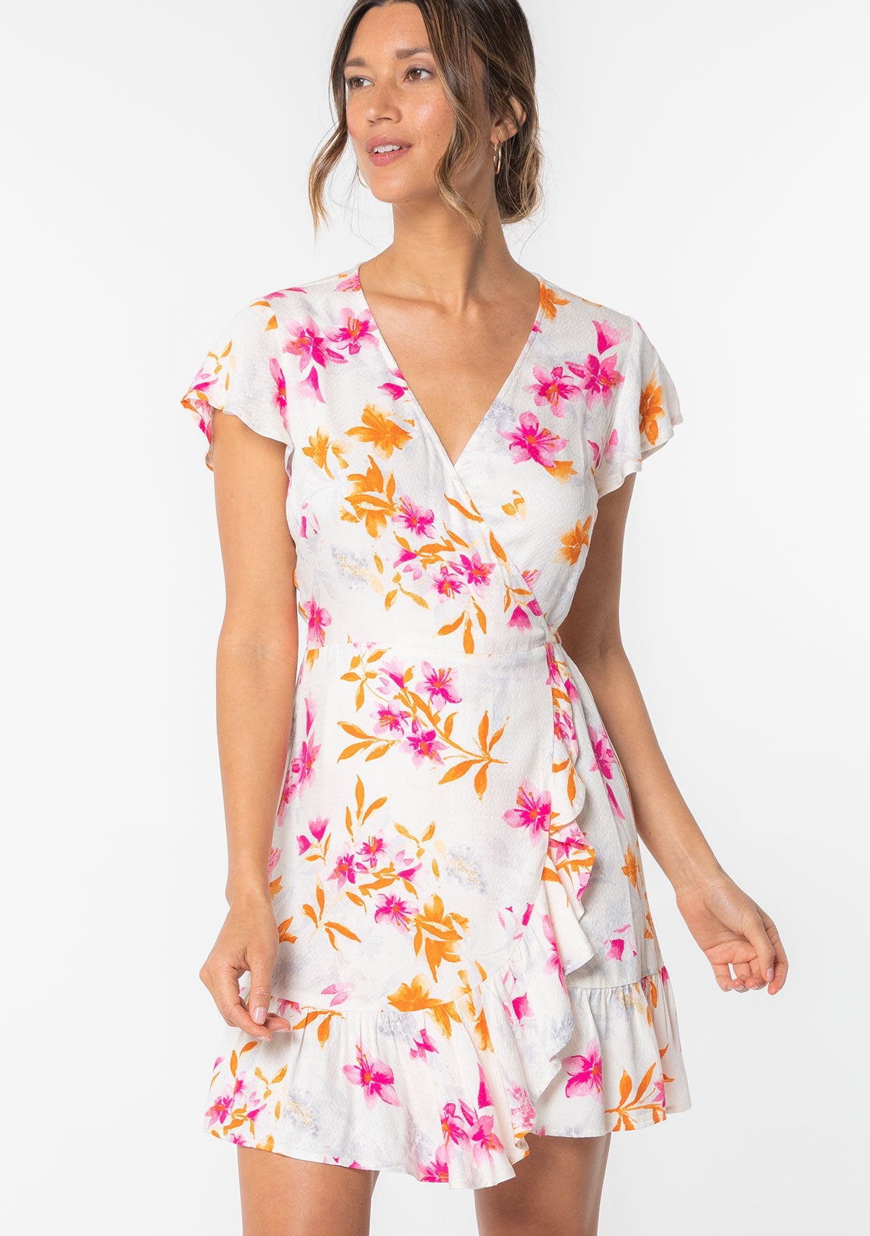[Color: Ivory/Fuchsia] A model wearing a white and pink floral print mini wrap dress with short flutter sleeves and ruffled hemline.