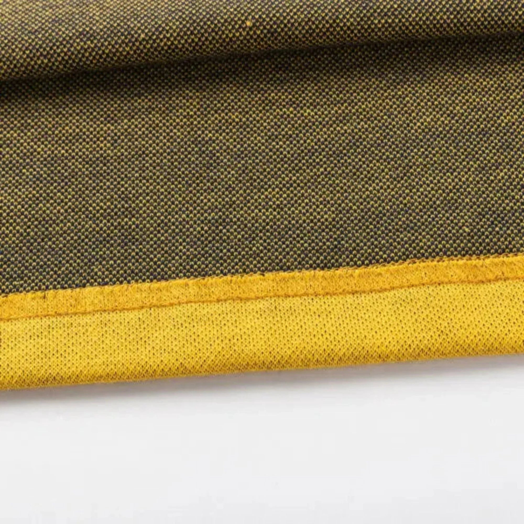 Close-up of a textured fabric with a yellow edge, resembling the Limited Edition Hurricanes Super Rugby 25/26 Retro Jersey by Classic Sportswear. The darker shade features small dotted patterns, capturing classic sportswear's essence.