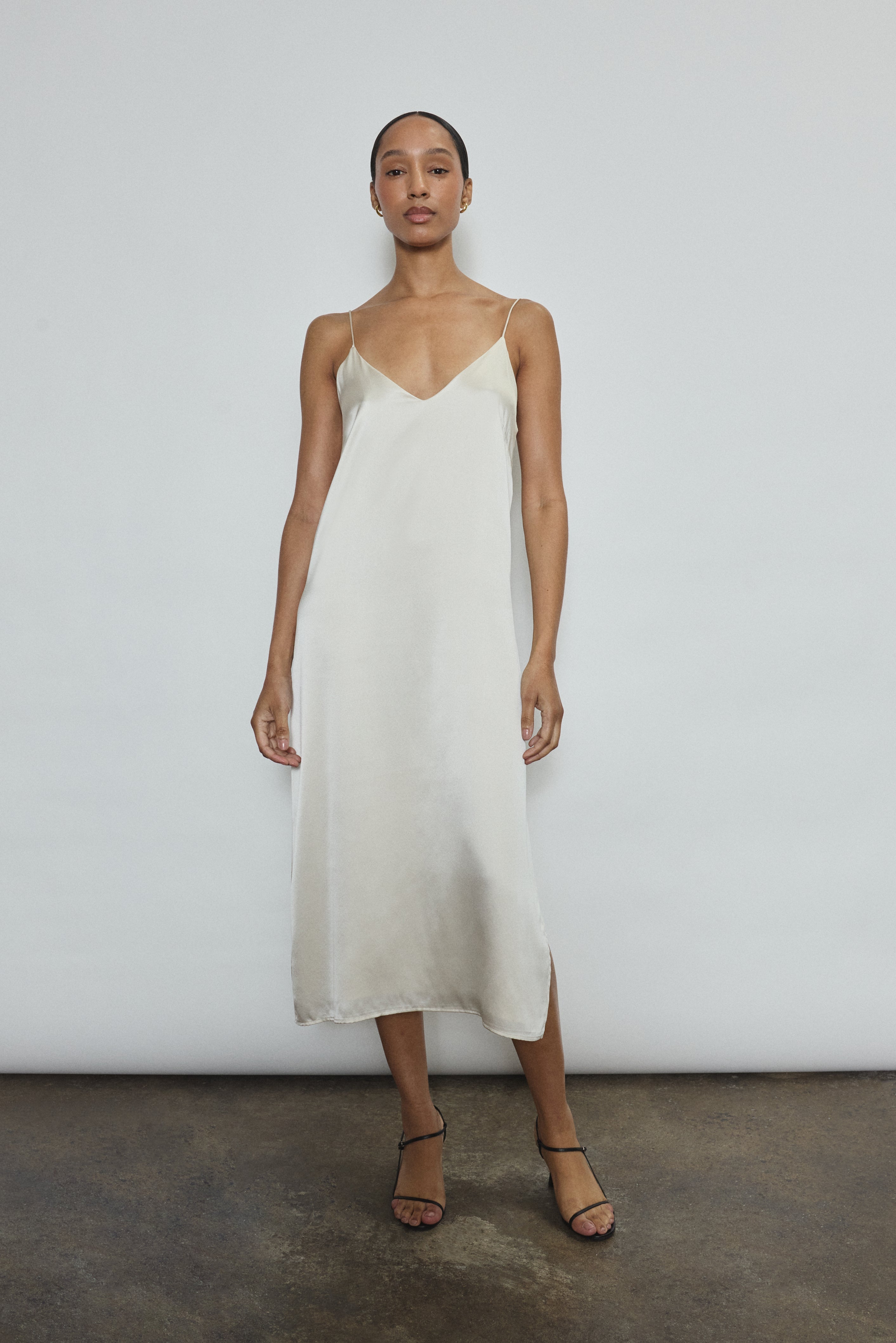 Front view of a model wearing the ivory silk charmeuse Kamperett Sade Slip Dress, a straight-cut midi with corded straps.