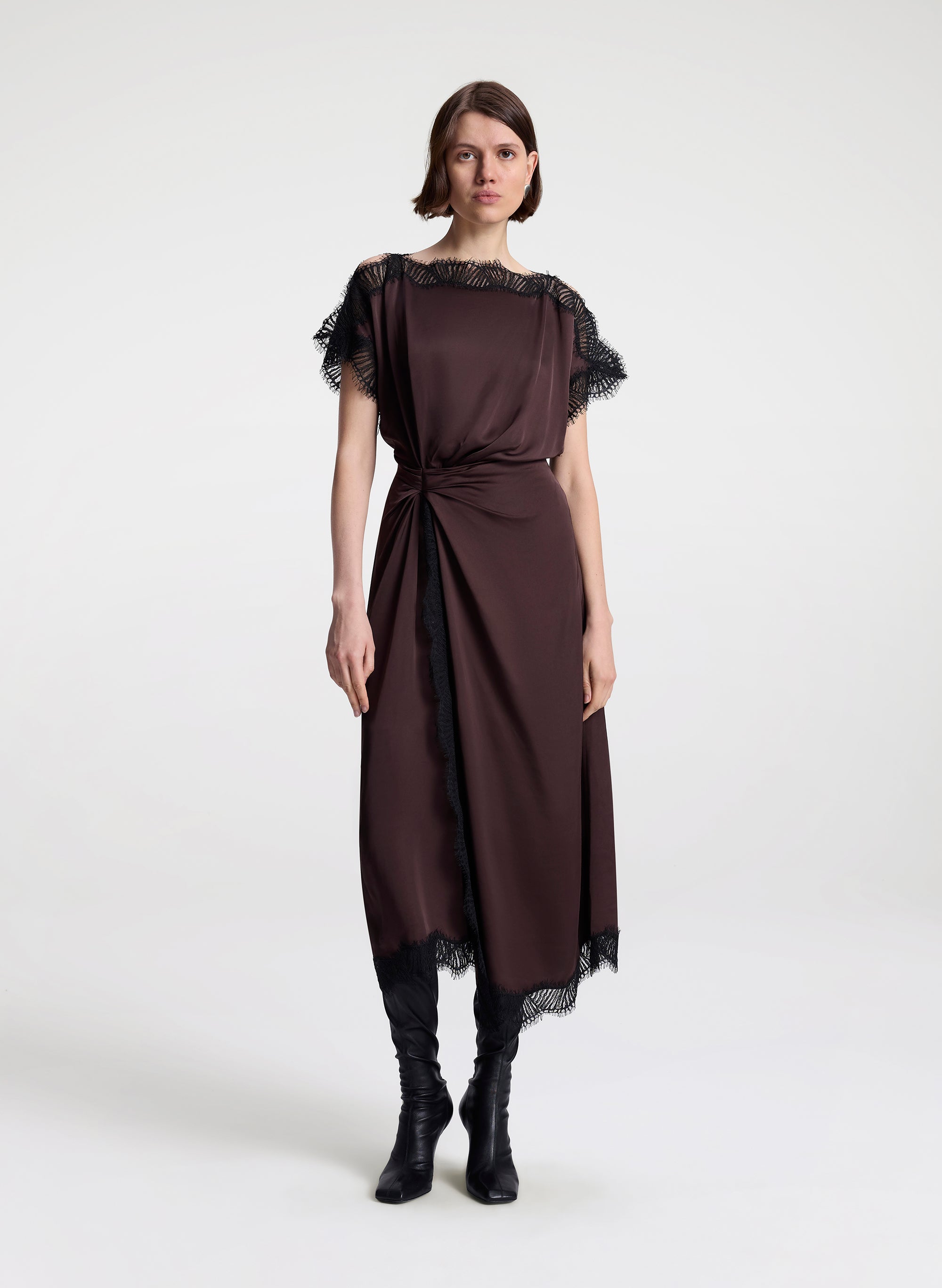 Woman wearing a brown dress with lace details on a white background