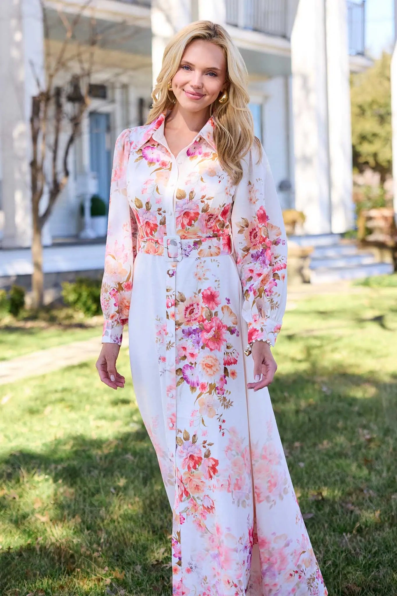 Woman wearing a floral dress standing outdoors with a house in the background