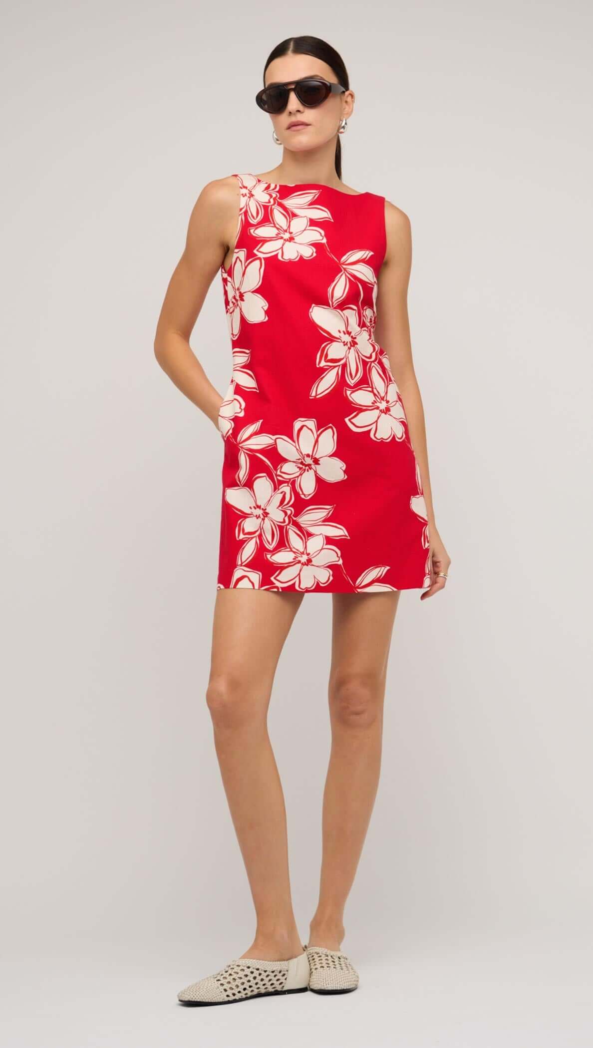 Model wearing a red and white floral mini shift dress, paired with sunglasses for a stylish summer look.