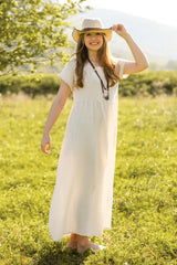 White empire waist maxi dress and straw hat in a grassy field — soft organic double gauze cotton