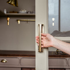 Hand opening a door with a brass handle in a kitchen setting