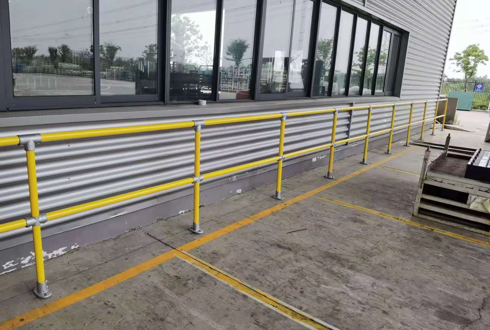 Gelbes Stahlrohr Geländersystem entlang einer Industriehalle montiert