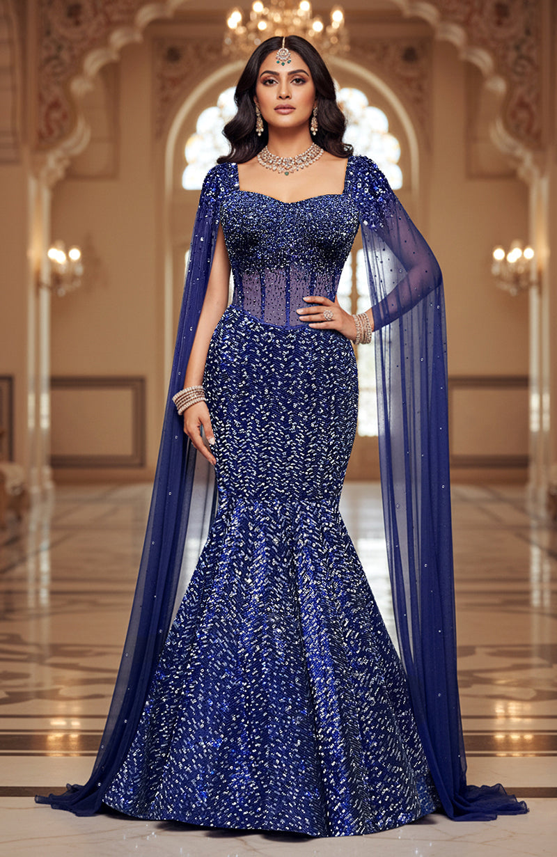 A sapphire blue sequined mermaid lehenga with a corset top and sheer cape.