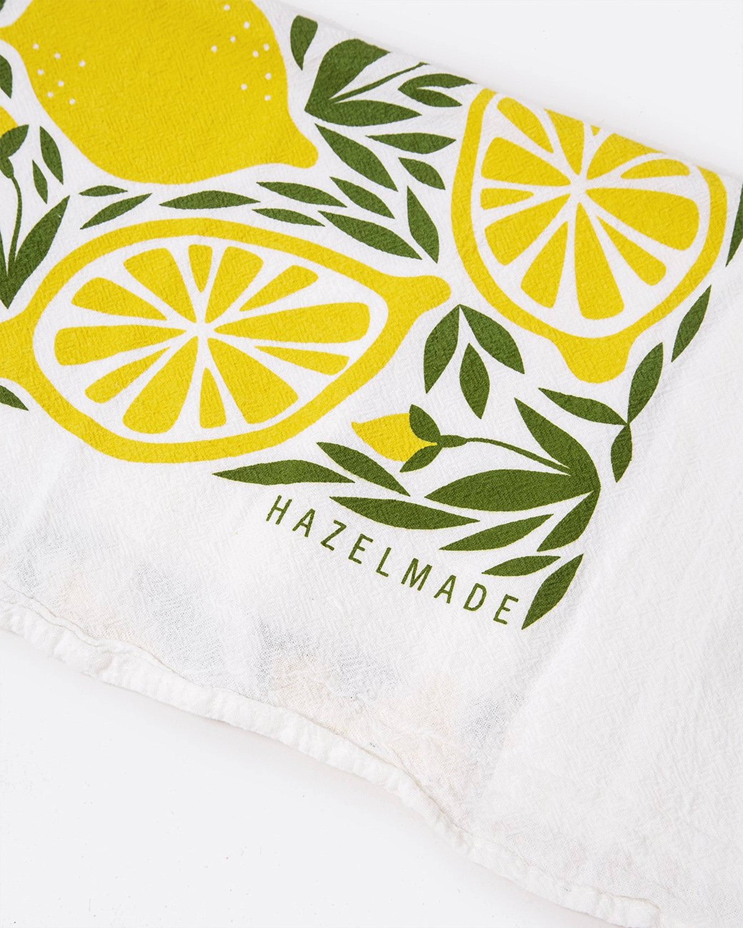 A tea towel with a lemon pattern. Shown folded close up.