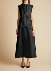 A sleeveless, black, maxi dress with pintuck detailing at the waist and covered buttons with a grosgrain guard. Includes a slip.